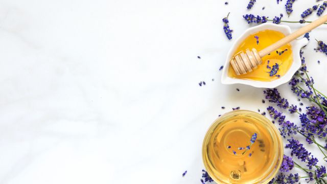 cup of lavender tea with honey and fresh flowers over white marble table. herbal drink. top view