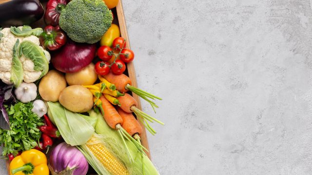 Fresh organic vegetables in wooden box on gray